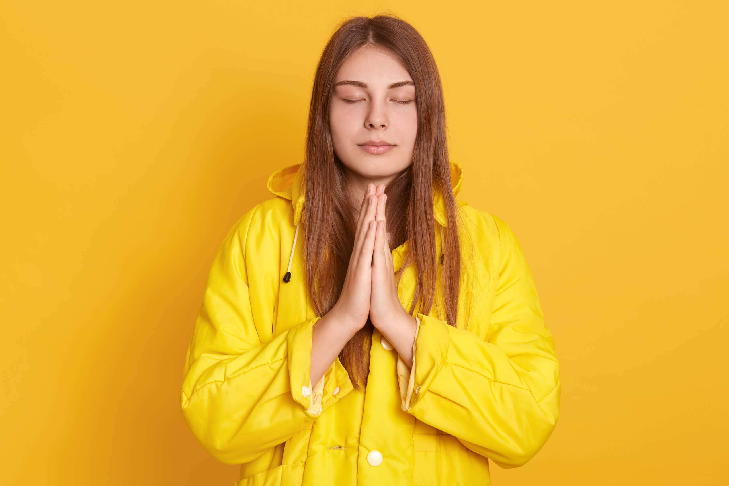 Horizontal shot of angry brunette woman posing isolated over yellow background, holding takeaway coffee cup, screaming while looking at camera, wearing casual t shirt, expressing negative emotions.